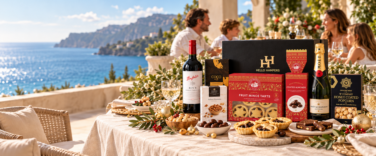 Styled Christmas table on a coastal terrace with a Hello Hampers gift box, wine, sparkling wine and festive treats